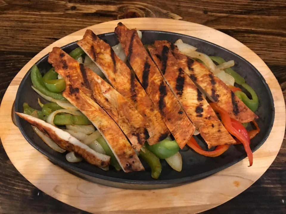 Chicken Fajitas - Sizzling grilled chicken with peppers and onions, served on a hot cast-iron skillet with rice, beans, and fresh tortillas.